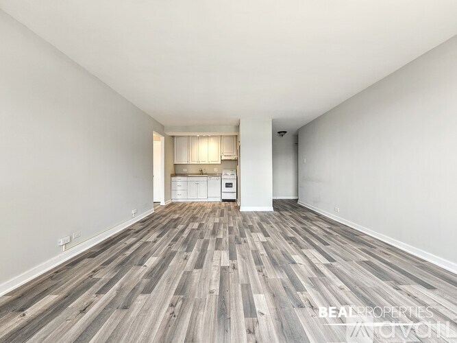 A spacious room with wooden flooring and white walls.
