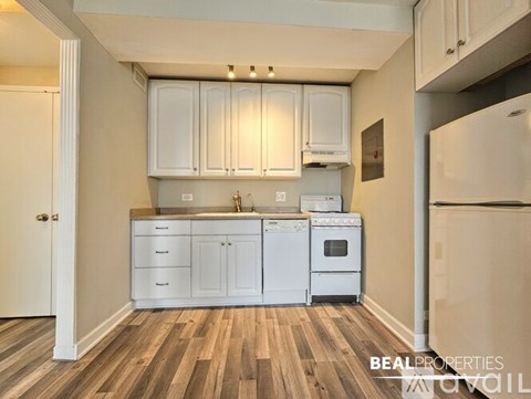 A kitchen with white cabinets and a wooden floor.