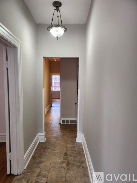 A hallway with a light fixture and a door at the end.
