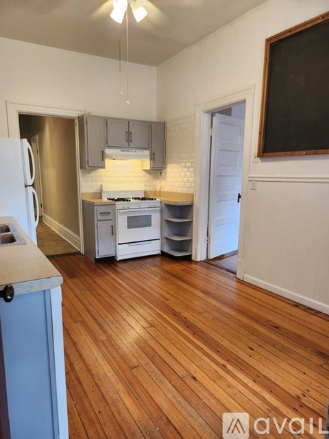 A kitchen with wooden floors and a white fridge.