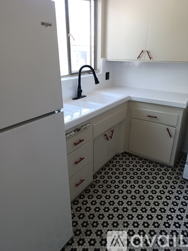 A white fridge in a kitchen with a black and white floor.