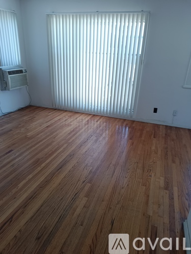 A room with wooden flooring and a window with blinds.