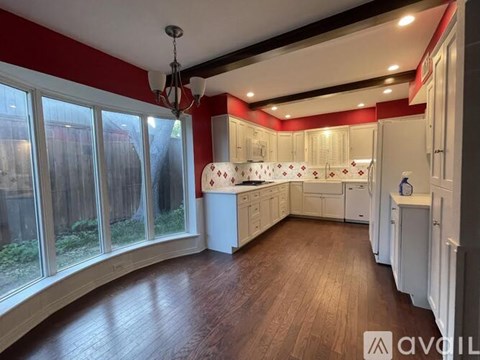 A kitchen with white cabinets and a wooden floor.