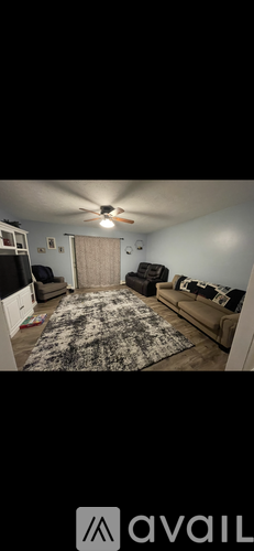A living room with a rug, a couch, and a ceiling fan.