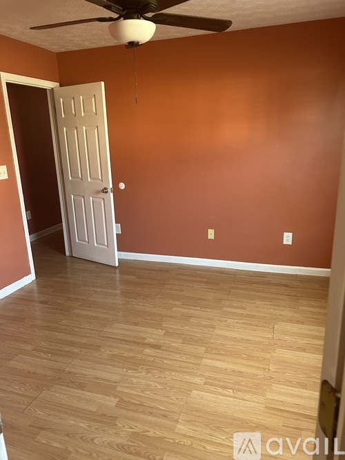 A room with a ceiling fan and a door.