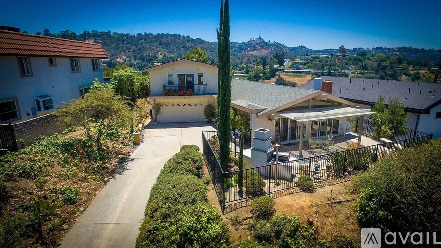 A house with a driveway and a tall cactus in front.