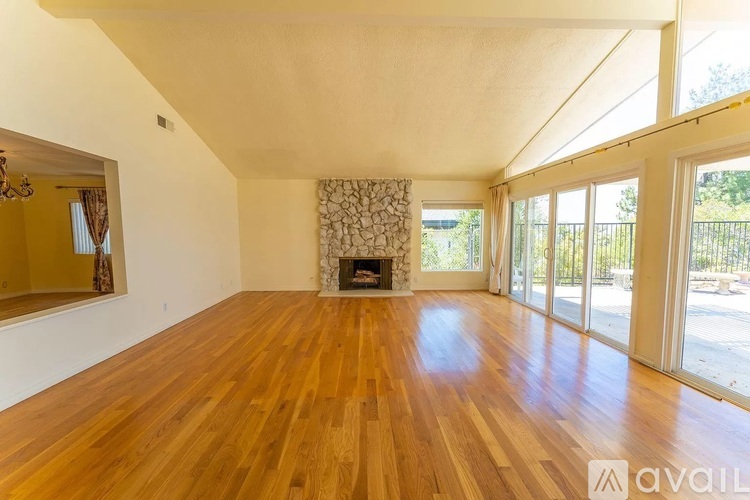 A spacious room with wooden floors and a fireplace.