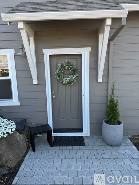 A grey house with a white door and a wreath on it.