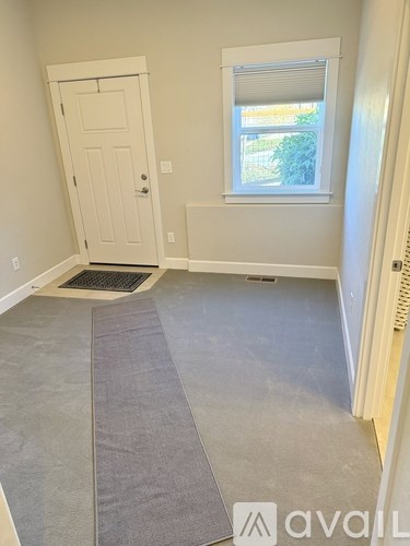 A room with a door, window, and a grey carpet.