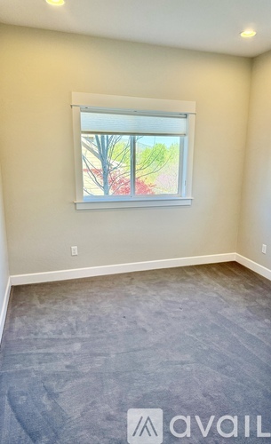 A room with a window showing trees and a building outside.