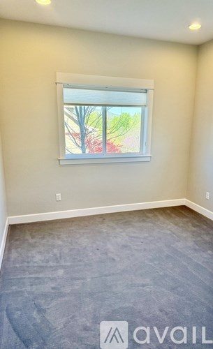 A room with a window showing trees and a building outside.