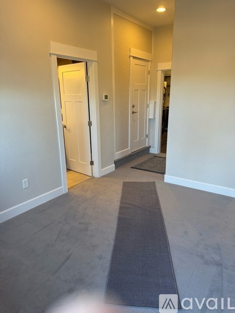 A hallway with a mat on the floor and two doors.
