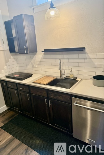 A kitchen with dark wood cabinets and a stainless steel dishwasher.