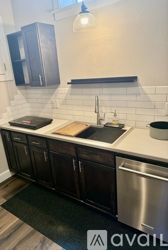 A kitchen with dark wood cabinets and a stainless steel dishwasher.