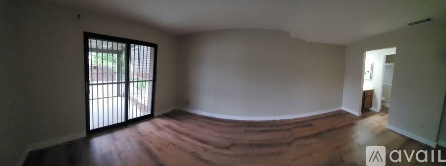 A room with wooden floors and a sliding door leading outside.