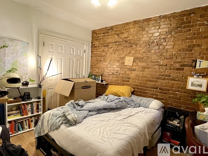A bedroom with a brick wall and a bed with a white comforter.