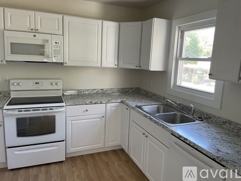 A kitchen with white cabinets and appliances.