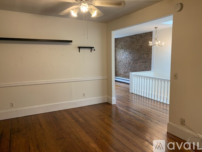 A room with wooden floors and a brick wall in the background.