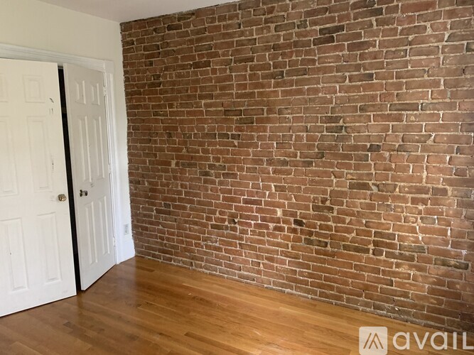 A room with a brick wall and wooden flooring.