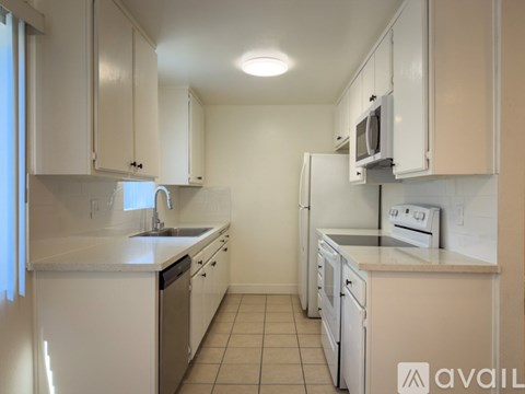 A kitchen with white cabinets and appliances.
