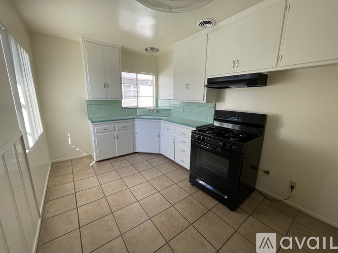 A kitchen with white cabinets and a black stove top oven.