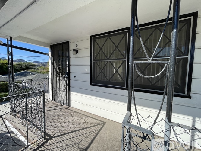 A balcony with a black railing and a window with a black diamond pattern.