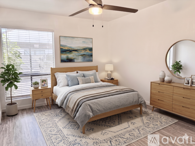 A bedroom with a bed, nightstand, and a plant.