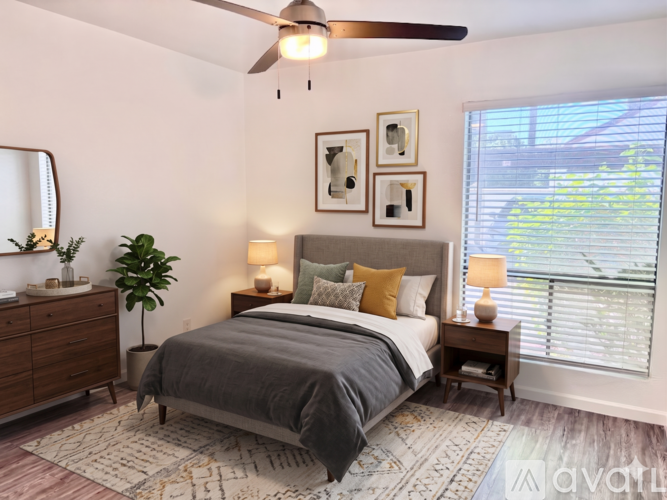 A bedroom with a bed, nightstand, and a plant.