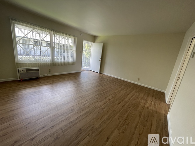 A room with wooden flooring and a window with blinds.