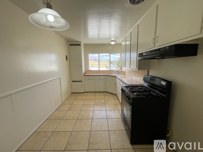 A kitchen with a black stove top oven and white cabinets.