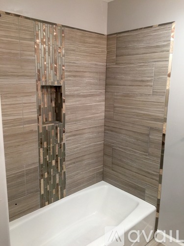 A bathroom with a tub and tiled walls.