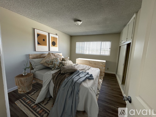 A bedroom with a bed covered in a grey blanket and pillows.