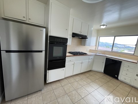 A kitchen with white cabinets and a stainless steel refrigerator.