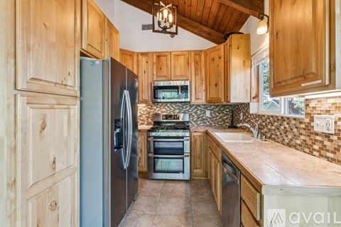 A kitchen with wooden cabinets and a stainless steel refrigerator.