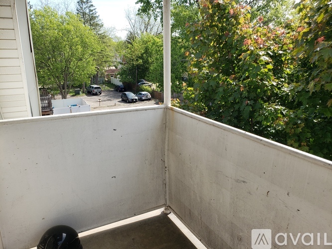 A balcony with a view of a street and trees.