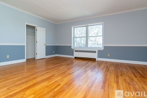 A room with wooden floors and a window with a view of trees outside.