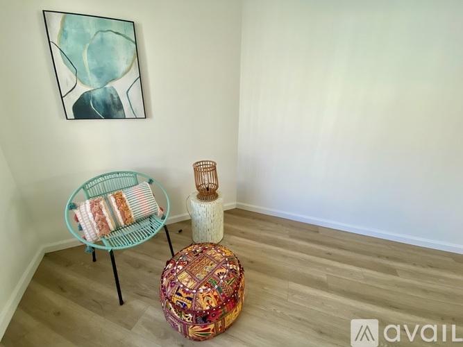 A room with a chair, a basket, and a woven ottoman.