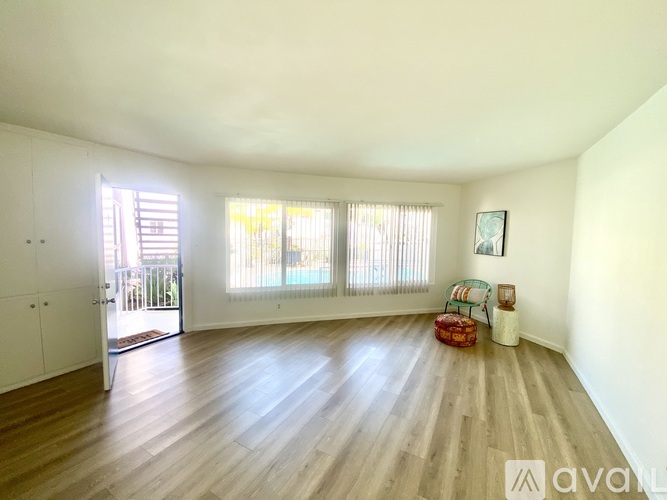 A room with wooden floors and a white ceiling with a window and a door.