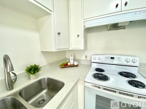 A white stove is in a kitchen with white cabinets.