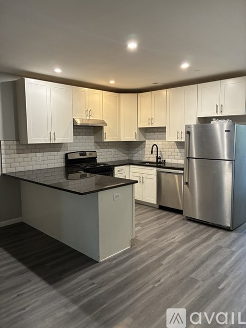A modern kitchen with a stainless steel refrigerator and a black countertop.