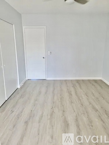 A room with a wooden floor and two white doors.