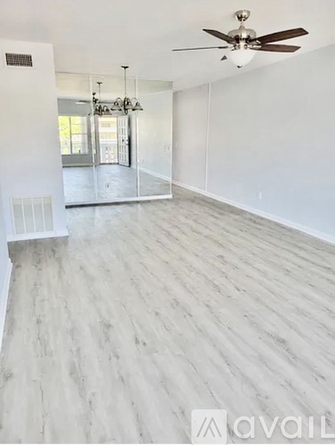 A spacious room with a ceiling fan and lighting fixture.