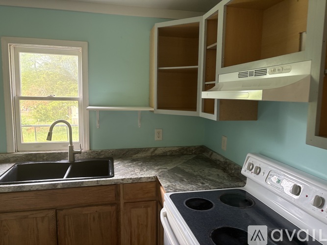 A kitchen with a white stove top oven and a black sink.