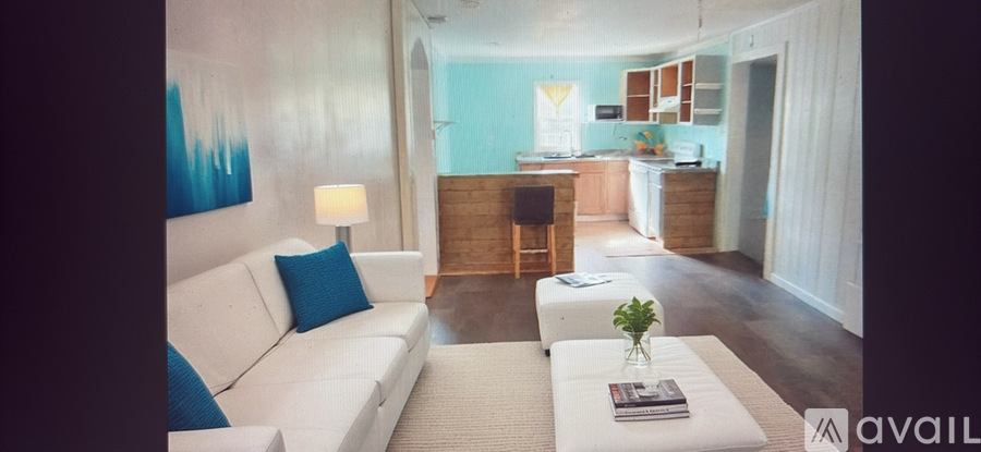 A living room with a white couch and a blue pillow.