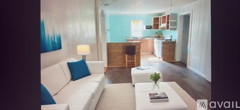 A living room with a white couch and a blue pillow.