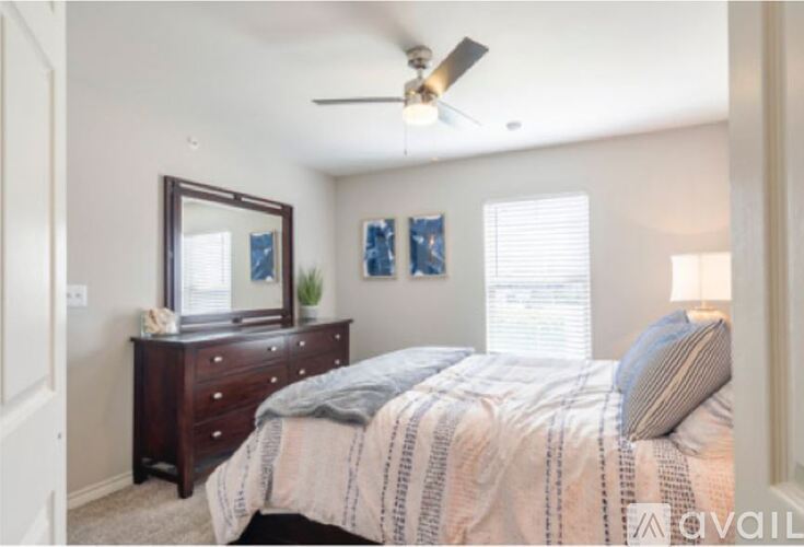 A bedroom with a bed, dresser, mirror, and two paintings on the wall.