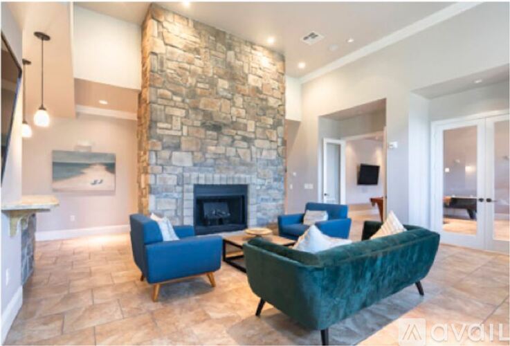 A living room with a stone fireplace and blue chairs.