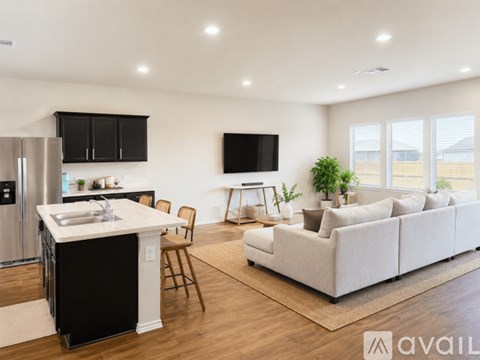 A modern kitchen with a refrigerator, sink, and a living room with a couch and a television.