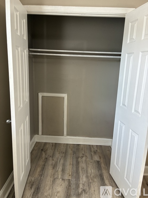 A small white closet with a shelf and a door.