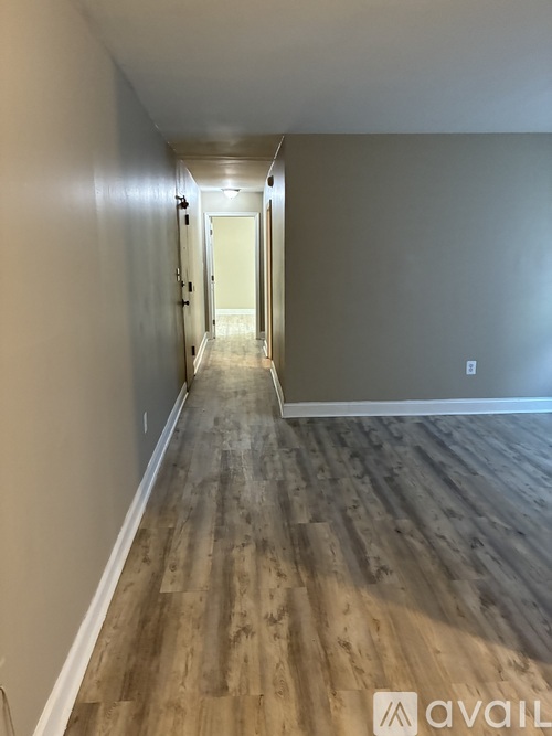 A long hallway with wood floors and a door at the end.